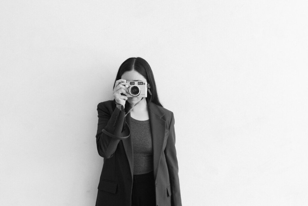 Woman photographer holding a contax g2 over her face wearing a professional outfit