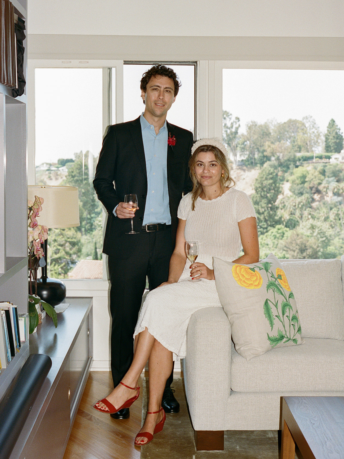 Newly married couple posing with wine glasses in a house.